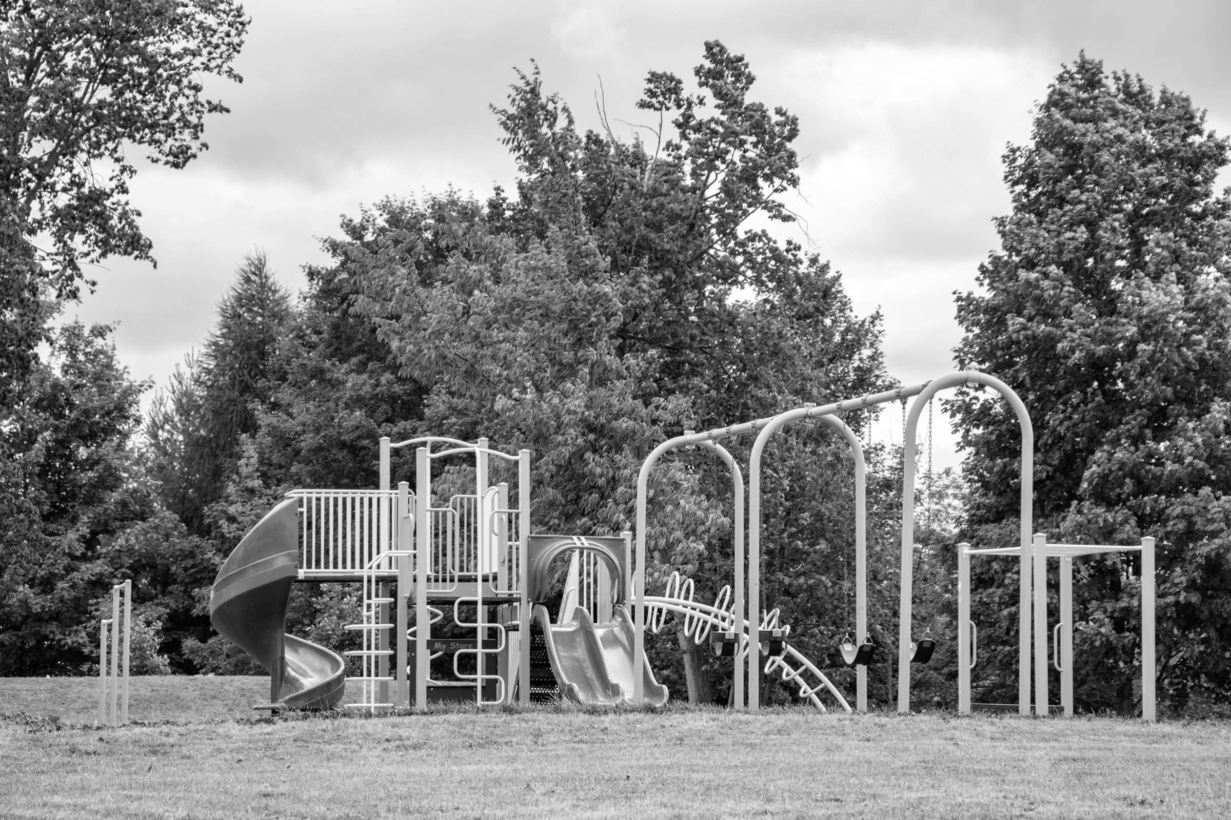 a photo of a playground surrounded by trees in the West End of Guelph