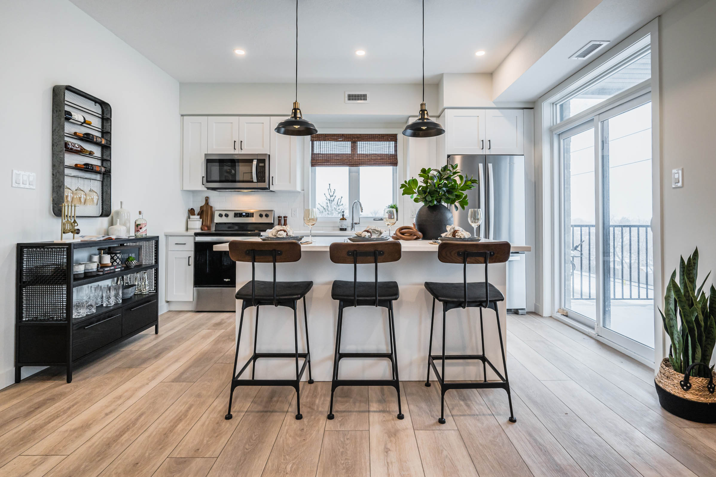 a photo of a staged model home kitchen looking head on at the island. white kitchen with stainless steel appliances and modern farmhouse decor