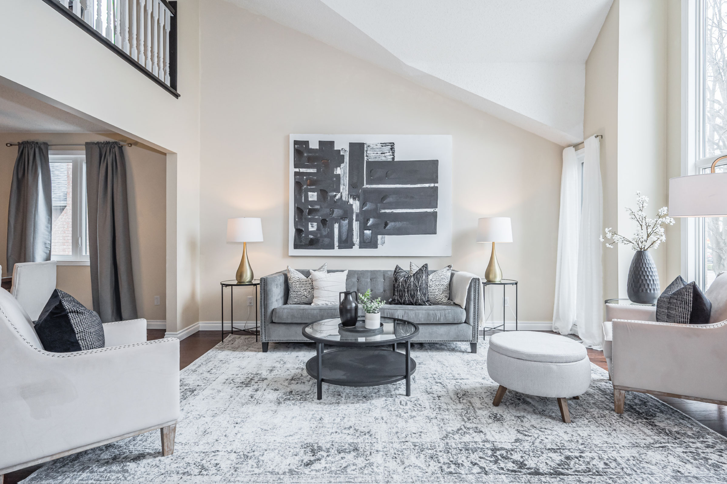 a well-designed living room in a house for sale in Guelph. The colours are black, white and grey. There is a couch, coffee table, 2 accent chairs, lamps and a nice big piece of art